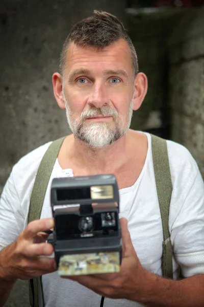 portrait of handsome bearded man with instant camera