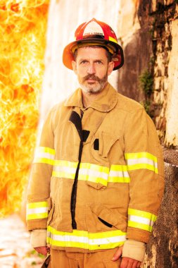 ateş duvarının önünde üniforma ayakta yakışıklı itfaiyeci portresi