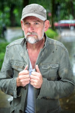 portre yakışıklı adam açık havada yağmur altında yürümek 50'li sakallı