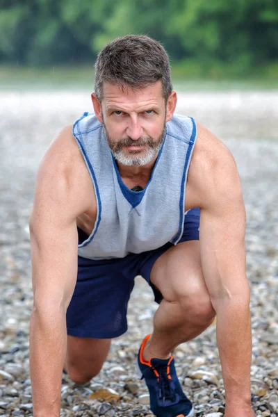 handsome bearded athlete getting ready to start running