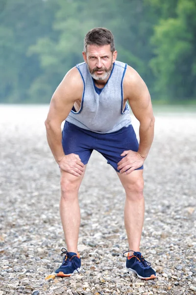 handsome bearded athlete taking a break to breath outdoors