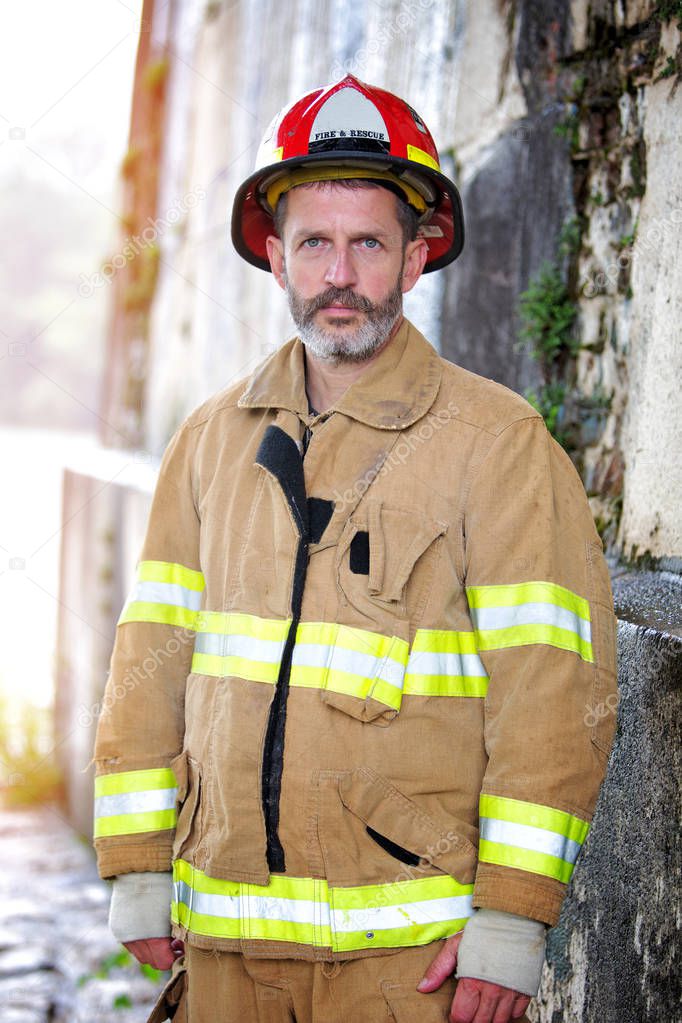 portrait of handsome fireman in uniform standing in front of wall