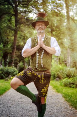 Bavyera adam açık havada yoga konumda ayakta ve meditasyon