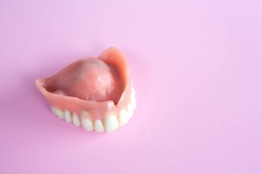 closeup of dental prosthesis on a pink background clipart