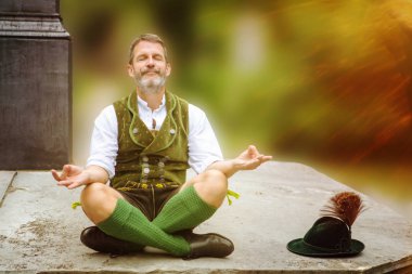 outddors duvar ve meditasyon oturan Bavyera adam