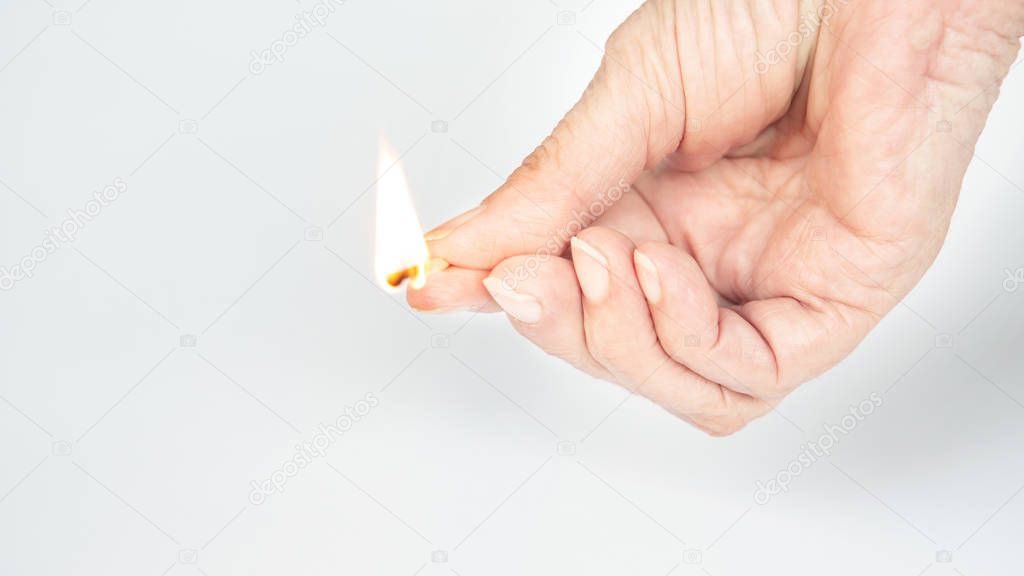 closeup of an older womans hand holding a burning matchstick