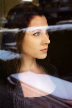 bir pencereden bakarak esmer genç kadın portresi