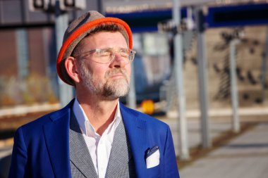 Tren istasyonunda duran ve güneşin tadını 50'li yakışıklı adam