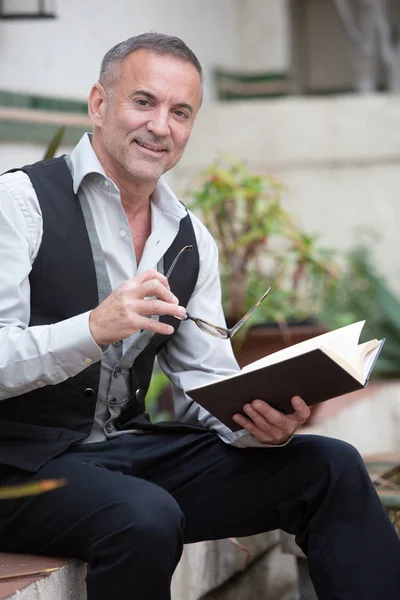 Handome uomo d'affari seduto fuori e la lettura di un libro — Foto Stock