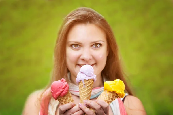 Young woman holding three ice cream cones and smiles — Stock Photo, Image