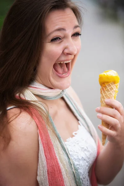 Jovem mulher ao ar livre segurando um cone de sorvete e rindo — Fotografia de Stock