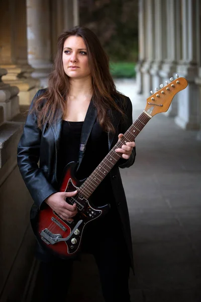 Jonge vrouw in zwart lederen jas spelen van de gitaar buiten — Stockfoto