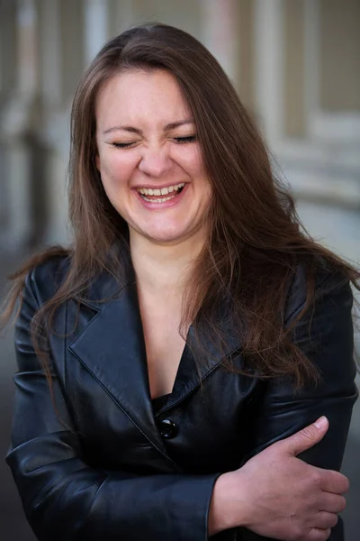 Jonge vrouw in lederen jas buiten staan en lachen — Stockfoto