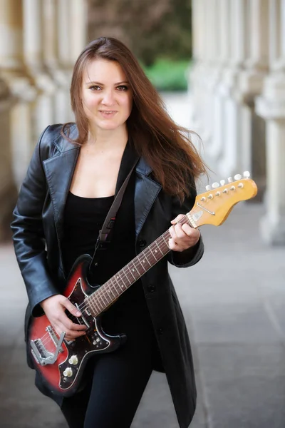 Young woman in black leather jacket playing the guitar outdoors — Stock Photo, Image