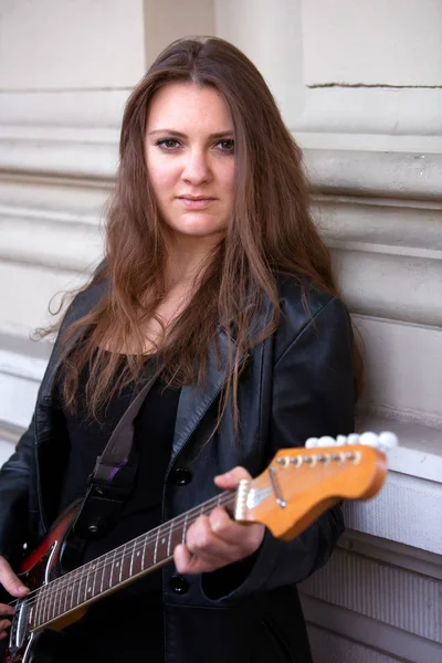Jeune femme en veste en cuir noir jouant de la guitare — Photo