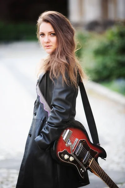 Jeune femme brune avec guitare dans la rue — Photo