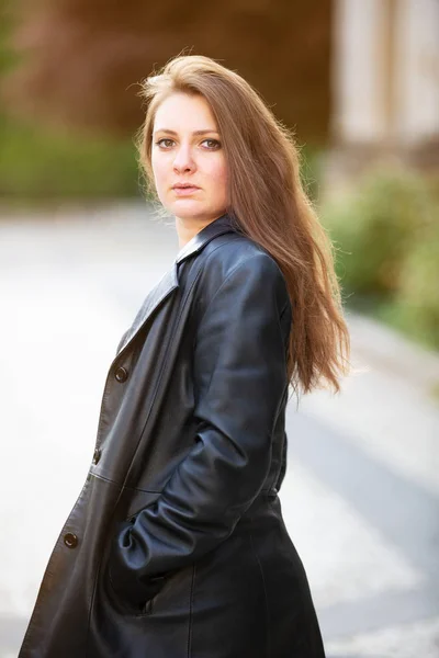 Young brunette woman in leather jacket standing outside — Stock Photo, Image