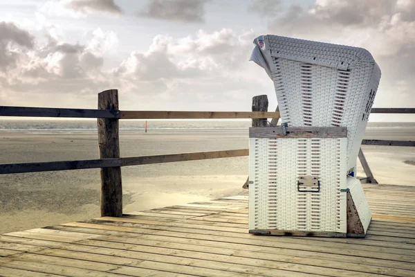 White wicker beach chair on wooden deck by the beach — Stock Photo, Image