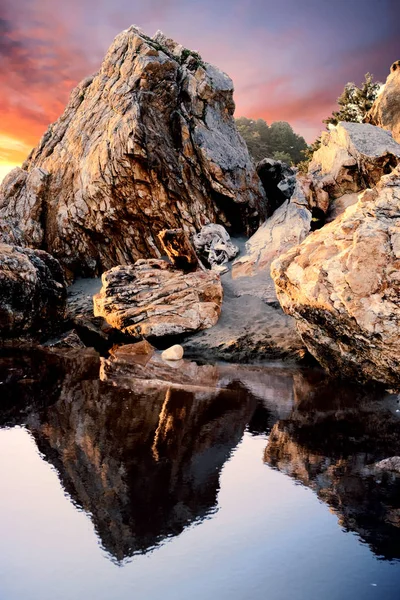 Utsikt över klippor som reflekteras i vattnet vid solnedgången — Stockfoto