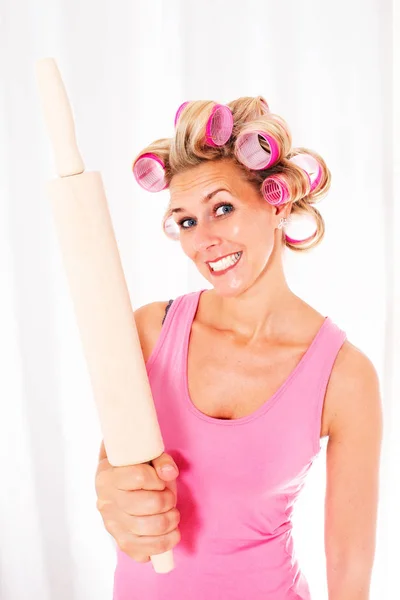 Blonde Frau mit Lockenwicklern, die ein sehr großes Nudelholz in der Hand hält — Stockfoto