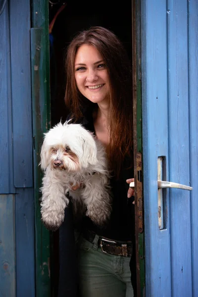 Jeune femme tenant son chien et debout à la porte bleue — Photo