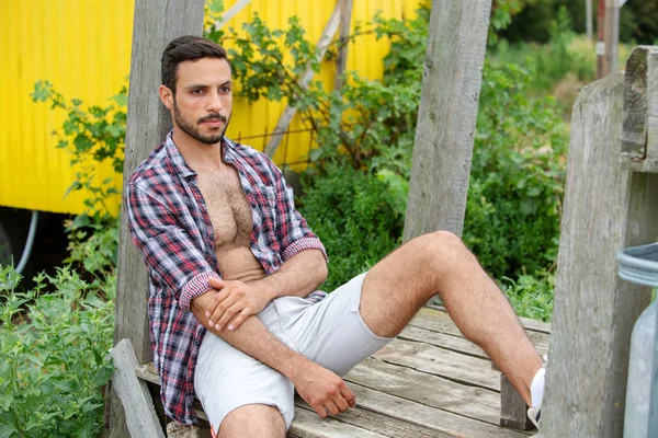 Portret van sexy man met open shirt zittend buitenshuis — Stockfoto