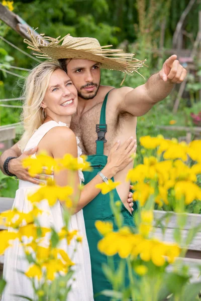 Çift bahçede dışarıda birbirlerine sarılma ve adam işaret — Stok fotoğraf