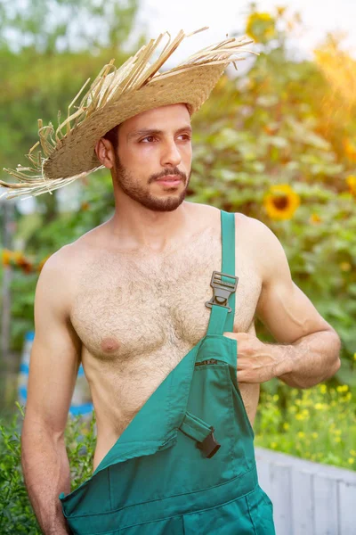 Jardineiro bonito com calças verdes e chapéu de palha de pé em gar — Fotografia de Stock