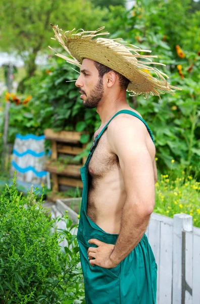 Knappe tuinman met groene broek en stro hoed staande in Gar — Stockfoto