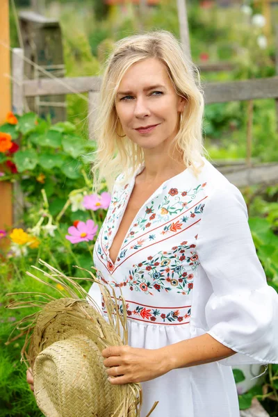 Bella donna bionda in abito bianco in piedi in giardino — Foto Stock