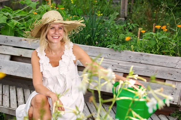 Bella donna bionda in abito bianco seduta fuori in giardino — Foto Stock