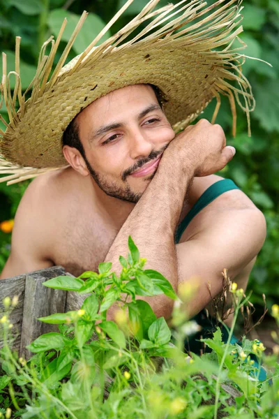 Portret van een bebaarde man met strohoed ontspannend in de tuin — Stockfoto