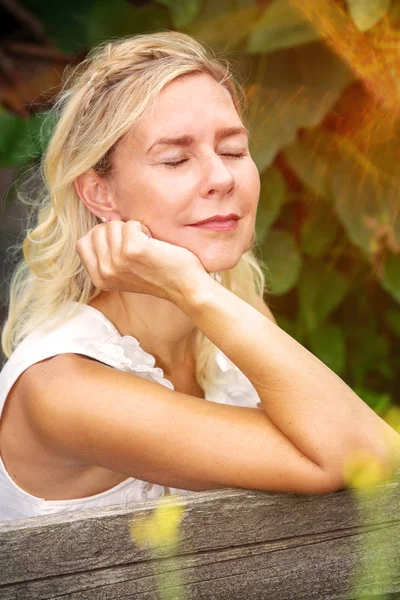 Ritratto di donna bionda seduta fuori e che si gode il sole — Foto Stock