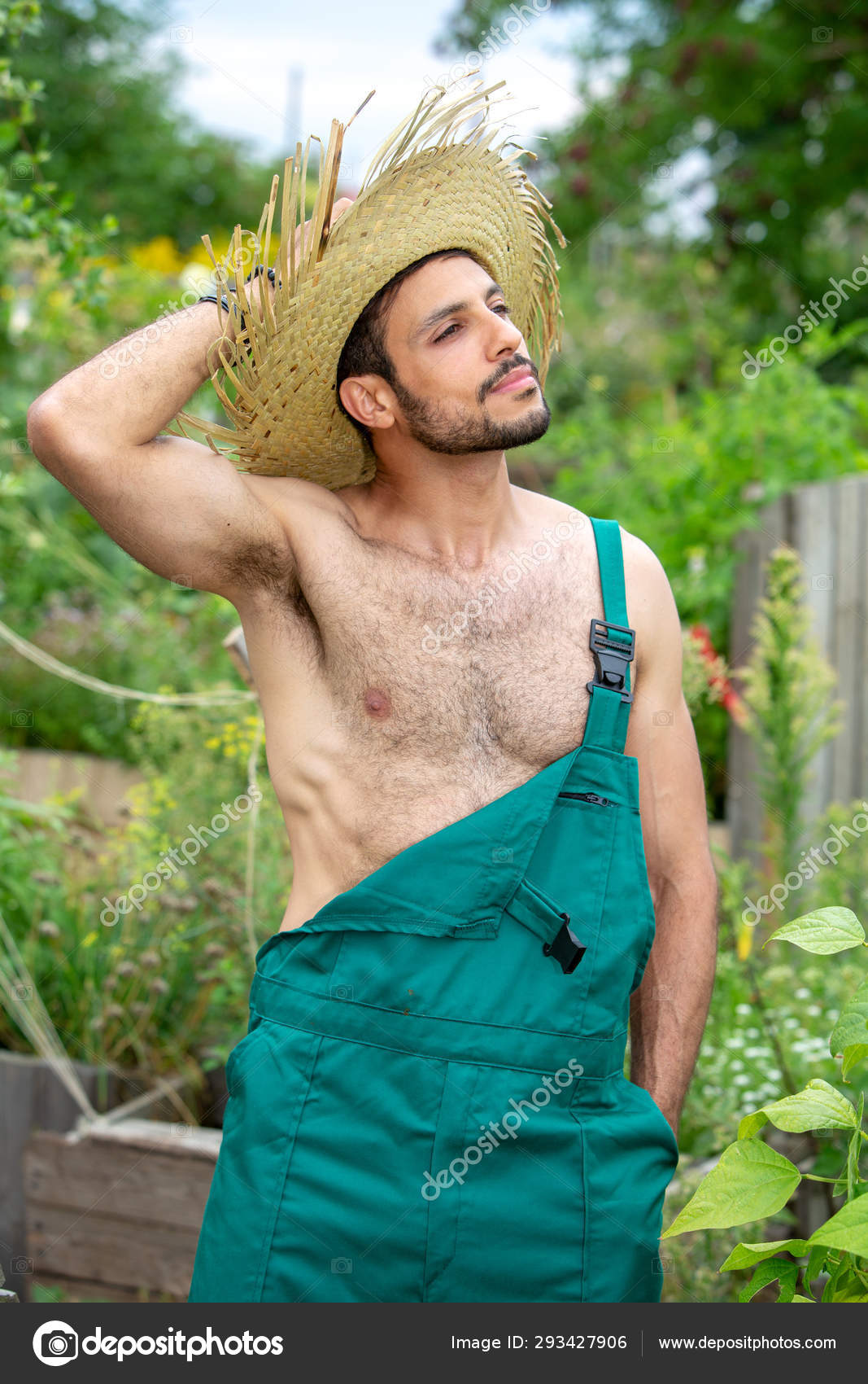 Hermoso jardinero con pantalones verdes y sombrero de paja de pie