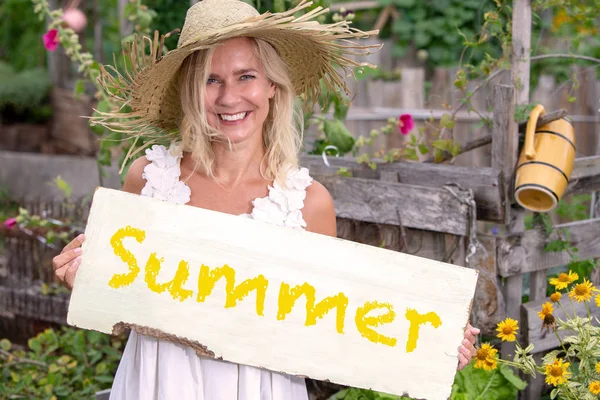 Donna bionda in piedi in giardino e tenendo il segno con la parola S — Foto Stock