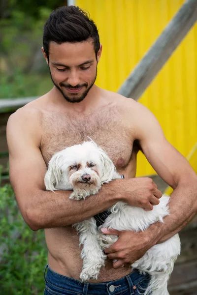 Portret van knappe shirtless man Holding een witte kleine hond — Stockfoto
