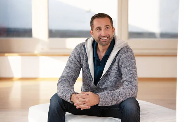 Handsome bearded man sitting indoor wearing a cardigan — Stock Photo, Image