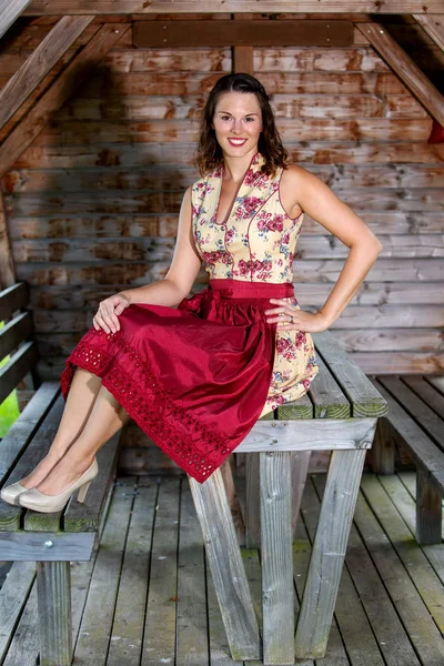 Bavarian mujer en dirndl sentado en una cabaña —  Fotos de Stock