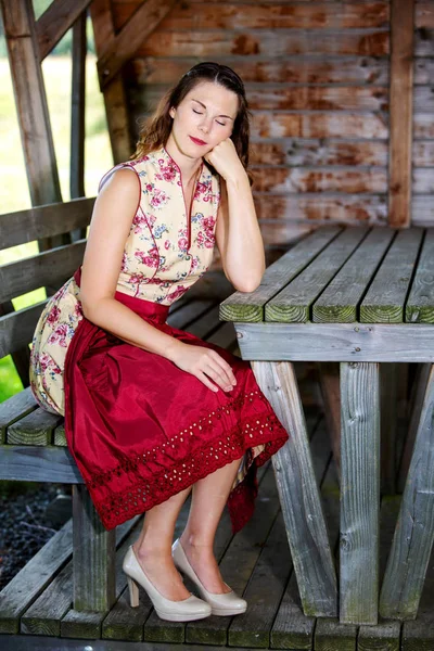 Bayerska kvinna i Dirndl sittande i en koja och sova — Stockfoto