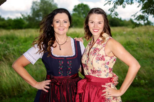 Two women in bavarian dirndl standing outdoors — Stock Photo, Image