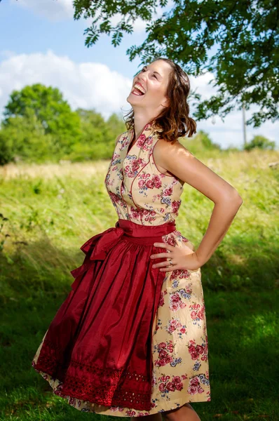 Ung kvinna i Dirndl stående av träd och skrattar — Stockfoto