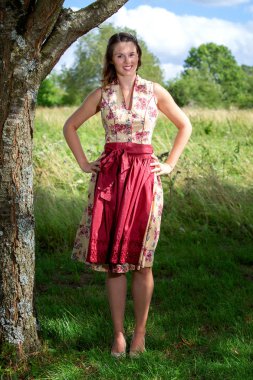 dirndl içinde genç kadın ağaç tarafından ayakta