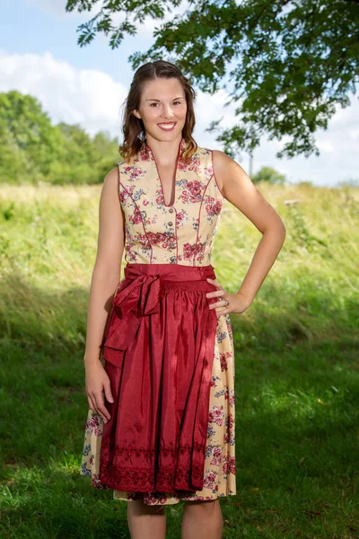 Jonge vrouw in Dirndl staande door boom — Stockfoto