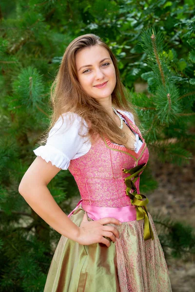 Young woman in dirndl standing by tree — Stock Photo, Image