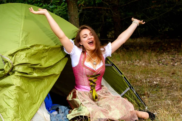 Junge Frau im Dirndl sitzt vor Zelt und breitet sich aus — Stockfoto