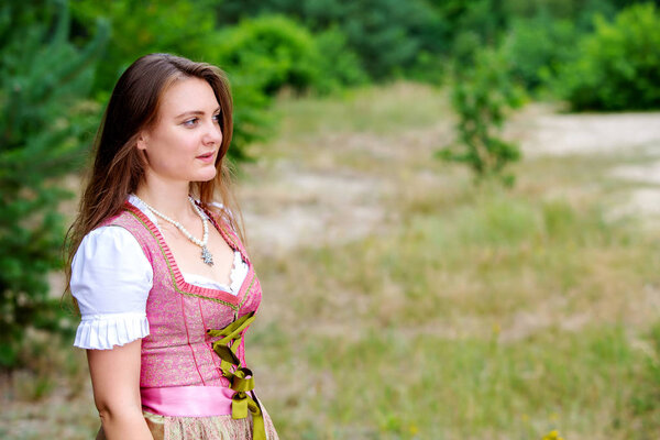  young woman in dirndl standing outdoors in meadow