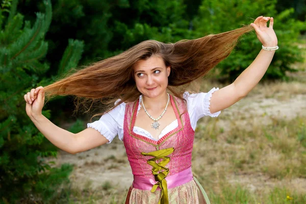 Junge Frau im Dirndl spielt mit ihren Haaren und macht Fratzen — Stockfoto