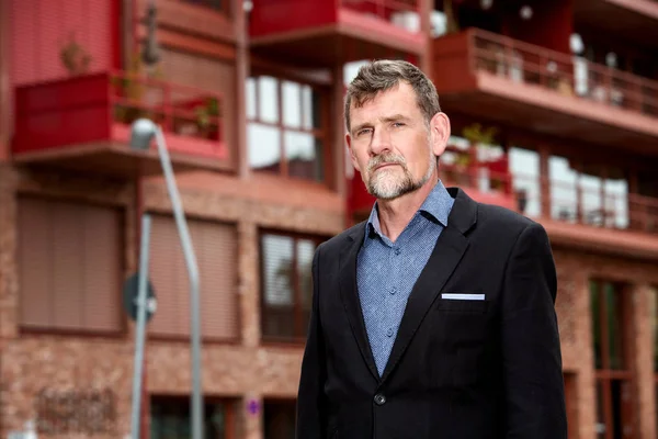 Hombre de negocios guapo en sus 50 años de pie frente al edificio — Foto de Stock