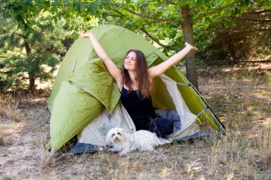 çadırının önünde oturan ve kollarını yayan genç kadın