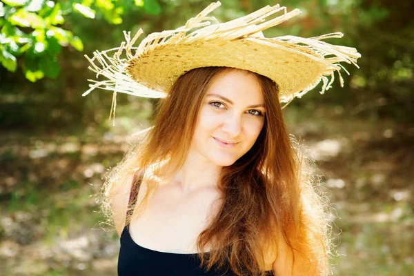Belle jeune femme brune avec chapeau de paille debout à l'extérieur — Photo